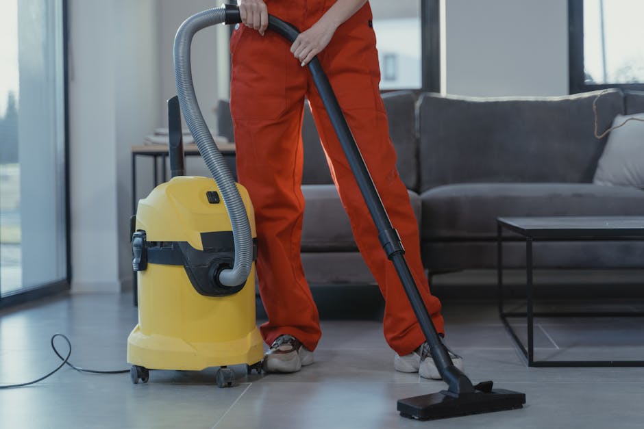 Two professional cleaning staff members from Edgware Cleaners are standing indoors against a plain white wall, dressed in beige uniforms with company badges. One is holding a red vacuum cleaner, and the other has a green mop, indicating their focus on surface cleaning and maintenance. Their attire and cleaning tools suggest they are preparing for or completing a deep cleaning or domestic cleaning task. The setting appears clean and well-lit, emphasizing hygiene and professional cleaning standards. This image highlights the expertise of Edgware Cleaners in providing comprehensive cleaning services near HA8 postcodes, ensuring surfaces such as floors and counters are thoroughly sanitised and maintained to high cleanliness standards.
